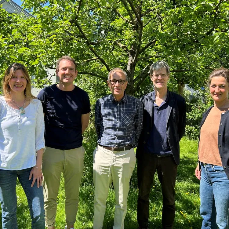 Fünf Personen vom Programmteam stehen lächelnd nebeneinander im Grünen vor einem Baum an einem sonnigen Tag.